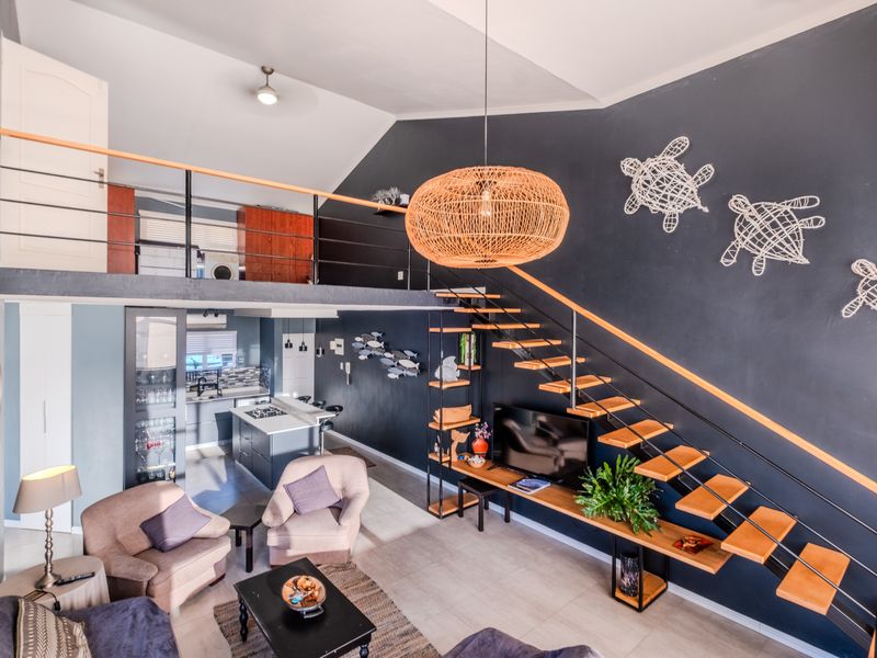 Spacious open-plan living area featuring a modern floating staircase, mezzanine level, and a well-appointed kitchen with a central island and contemporary finishes.