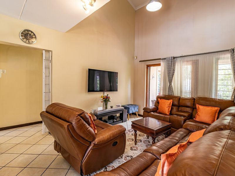 Spacious living room featuring high vaulted ceilings, ceramic tile flooring, and direct access to the outdoor area through a sliding glass door.