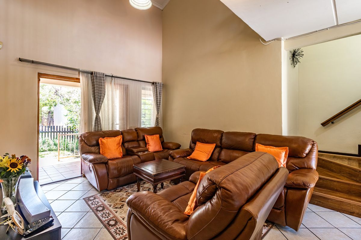 Spacious living room featuring high vaulted ceilings, tiled flooring, and direct access to an outdoor patio area via a sliding glass door.