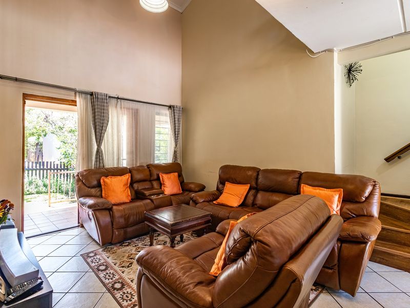 Spacious living room featuring high vaulted ceilings, tiled flooring, and direct access to an outdoor patio area via a sliding glass door.
