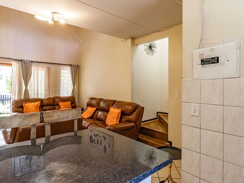 Open plan living area featuring a granite breakfast counter, tiled wall section, and direct access to a wooden staircase and outdoor patio.