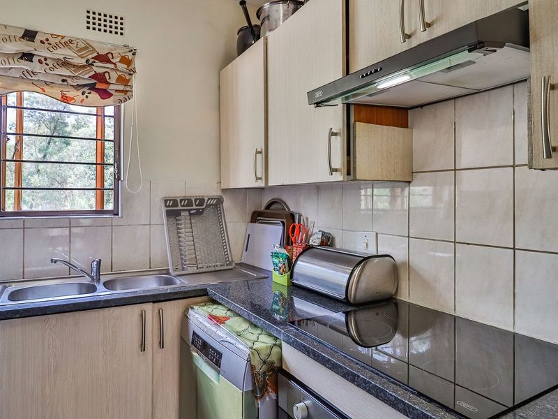 Functional kitchen featuring laminate cabinetry, double basin sink, tiled backsplash, and built-in electric hob with extractor fan.