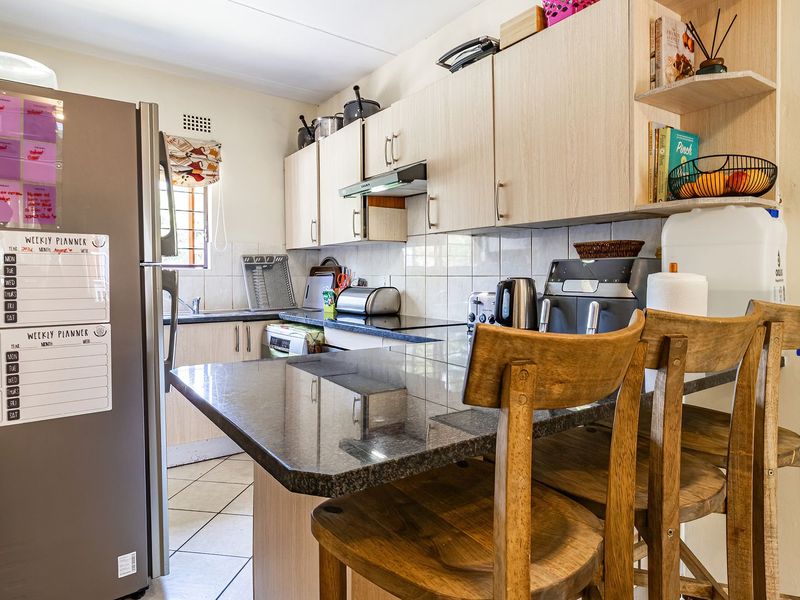 A functional kitchen featuring granite countertops, a breakfast bar, ample built-in cabinetry, and tiled flooring, providing a practical workspace for daily cooking and dining.