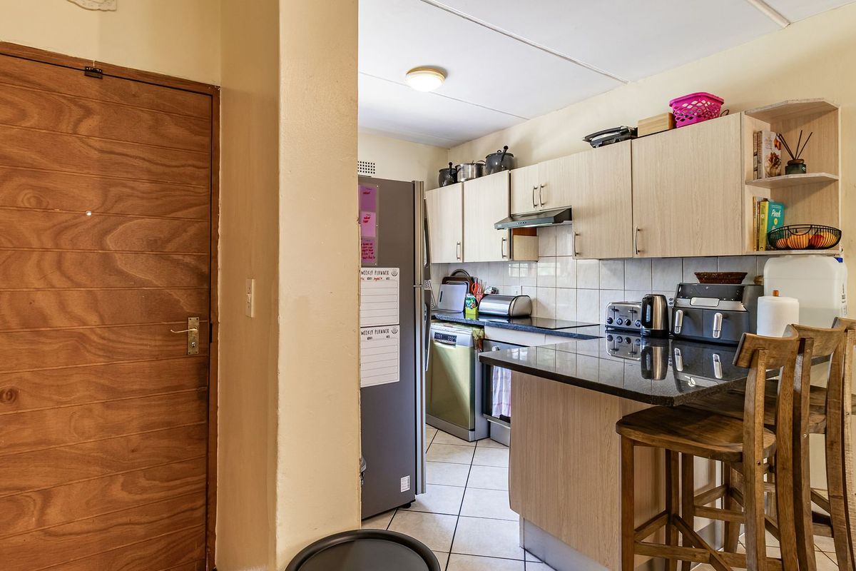 A functional kitchen featuring light wood-finish cabinetry, granite countertops, a breakfast bar, and tiled flooring, providing a practical layout for daily meal preparation.