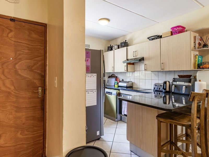 A functional kitchen featuring light wood-finish cabinetry, granite countertops, a breakfast bar, and tiled flooring, providing a practical layout for daily meal preparation.
