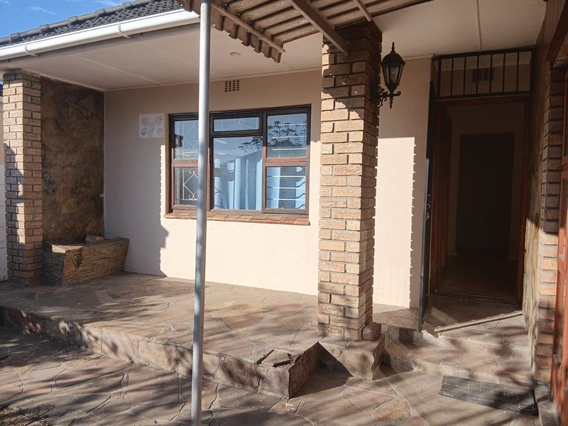 A covered patio area featuring stone paving, brick pillars, and stone cladding, providing a functional outdoor entrance space.