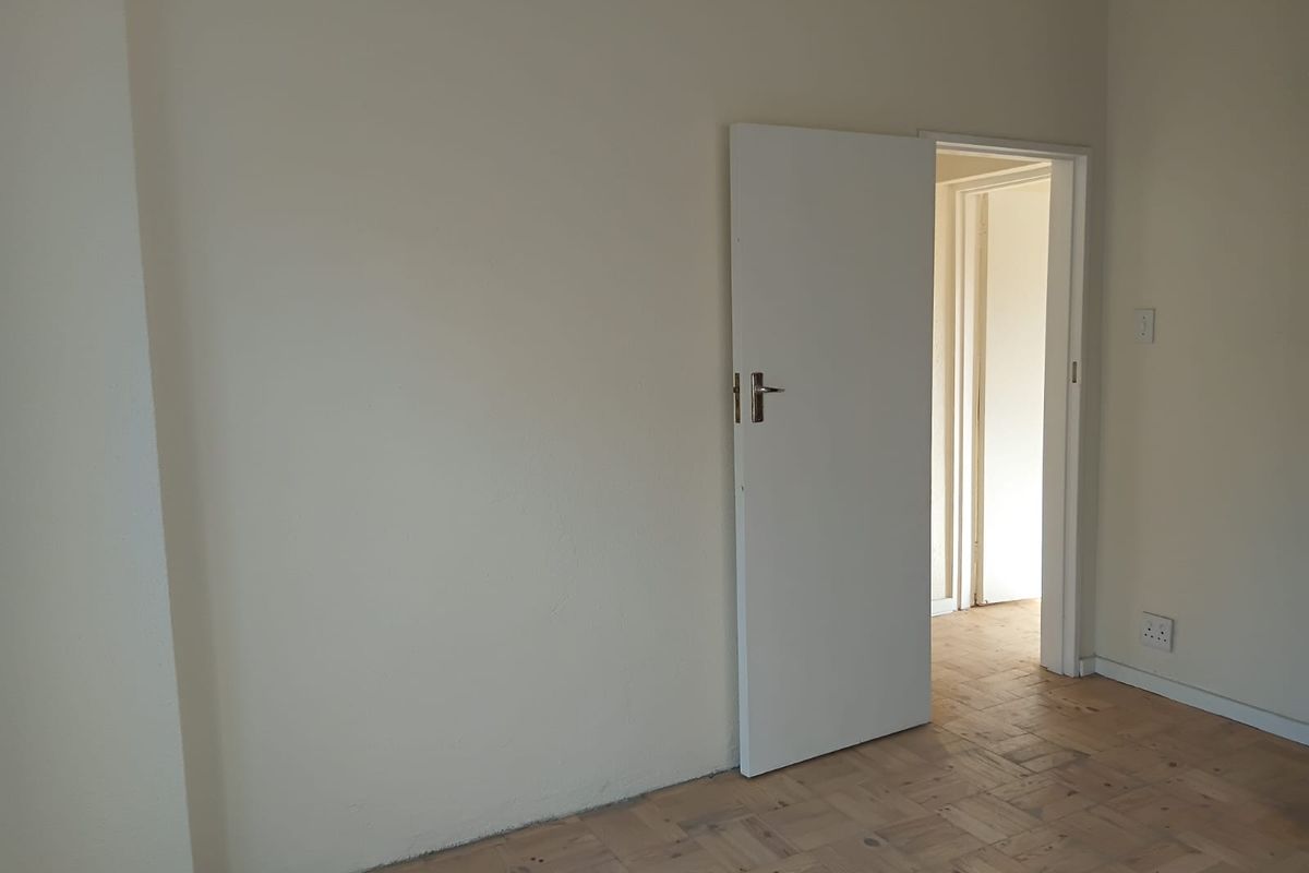 An empty bedroom featuring parquet flooring and neutral wall finishes, providing a blank canvas for personalization.