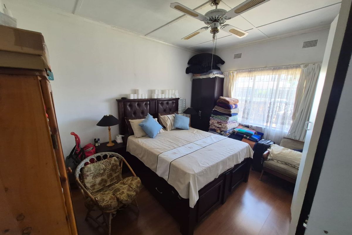 A bedroom featuring laminate flooring and a ceiling fan, currently showing signs of wear including visible ceiling panel damage.
