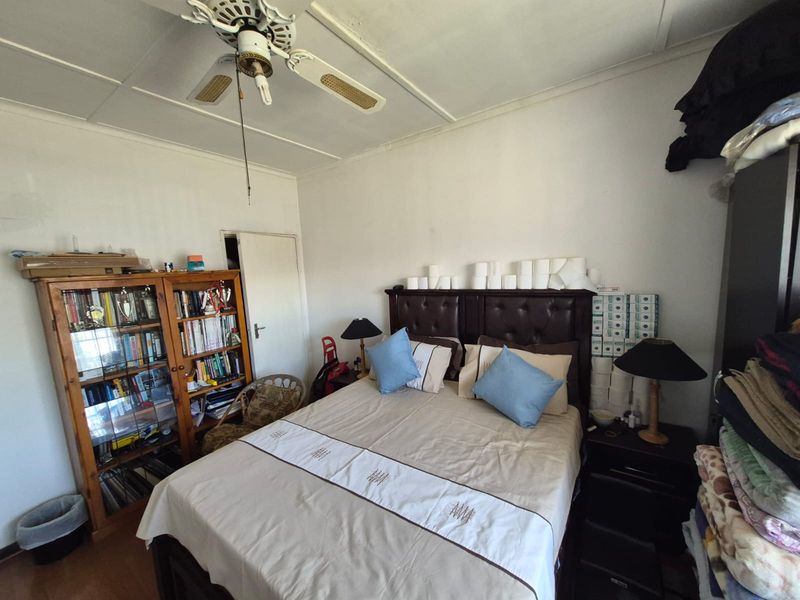 A bedroom featuring a ceiling fan and standard finishes, currently showing signs of wear and requiring cosmetic updates.