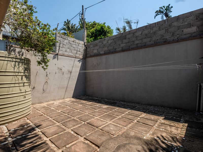 A private rear courtyard featuring paved flooring, a water storage tank, and perimeter walling with electric fencing.