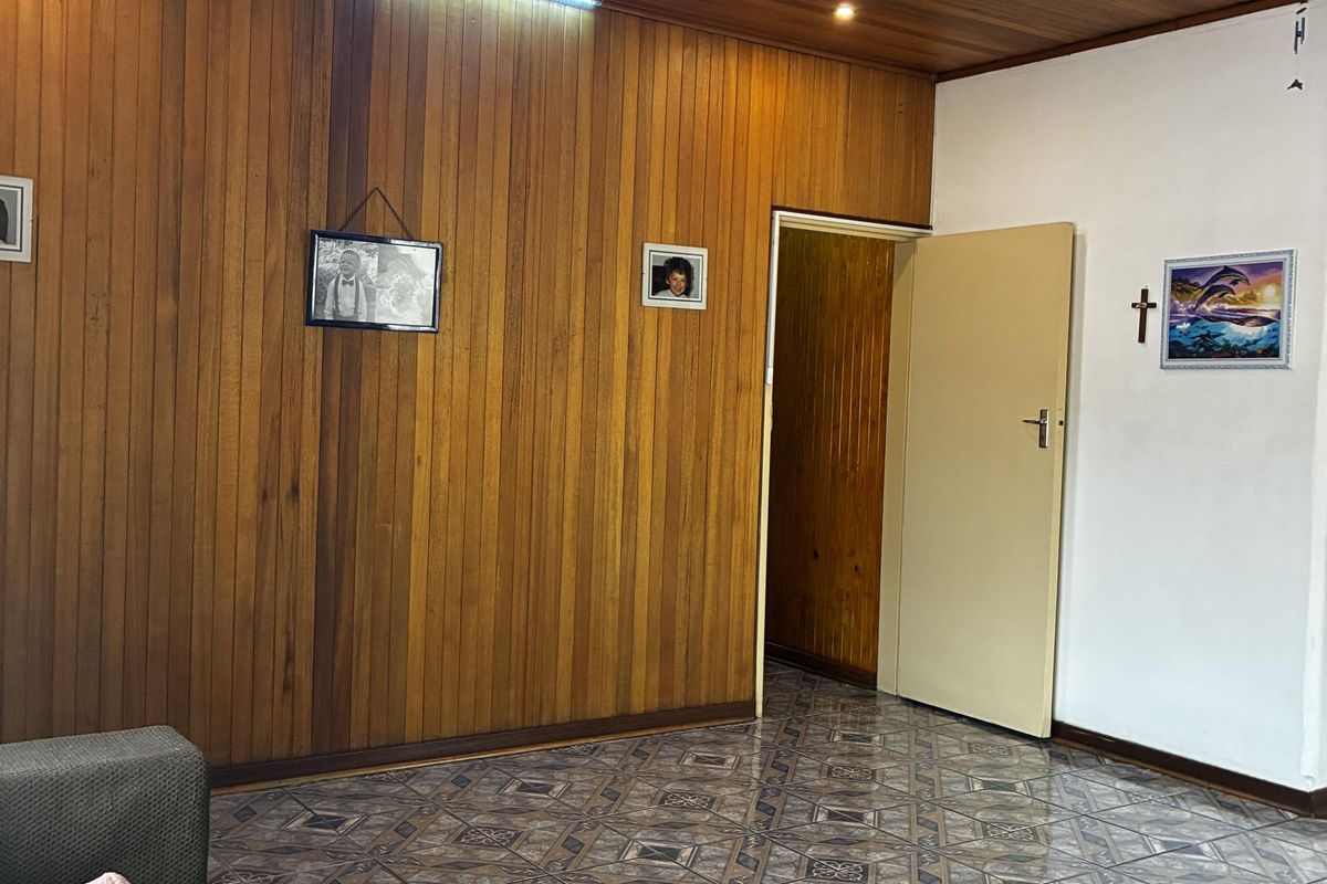 Living area featuring timber wall paneling, a matching timber ceiling, and patterned ceramic floor tiles.