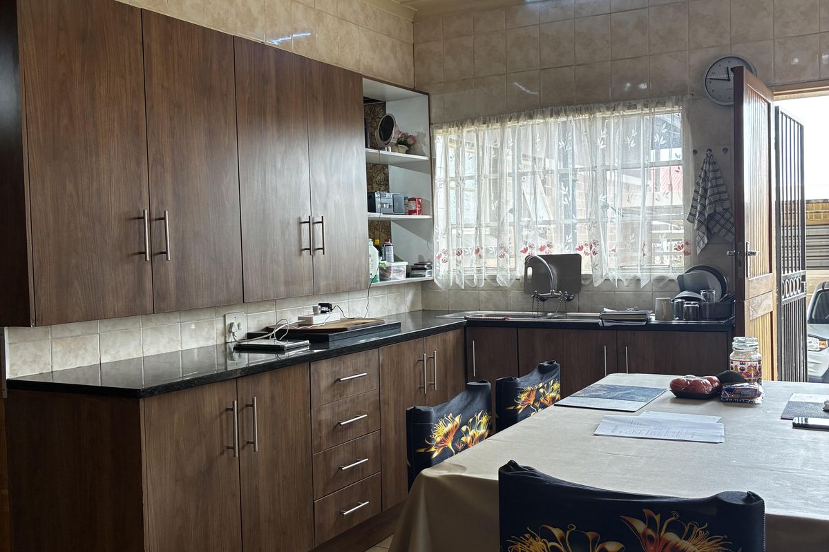 A functional kitchen featuring wood-finish cabinetry, granite countertops, tiled backsplash, and tiled flooring, offering a practical layout with ample storage space.