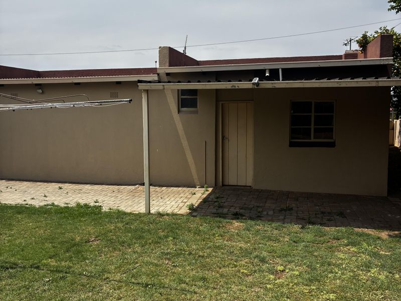 Rear view of the property featuring a paved patio area, covered veranda, and a private garden space.