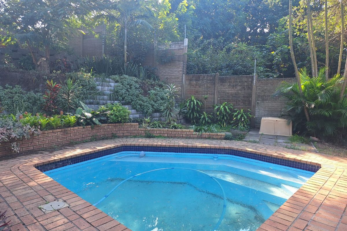 A private swimming pool area featuring brick coping, a tiered brick retaining wall, and established garden landscaping.