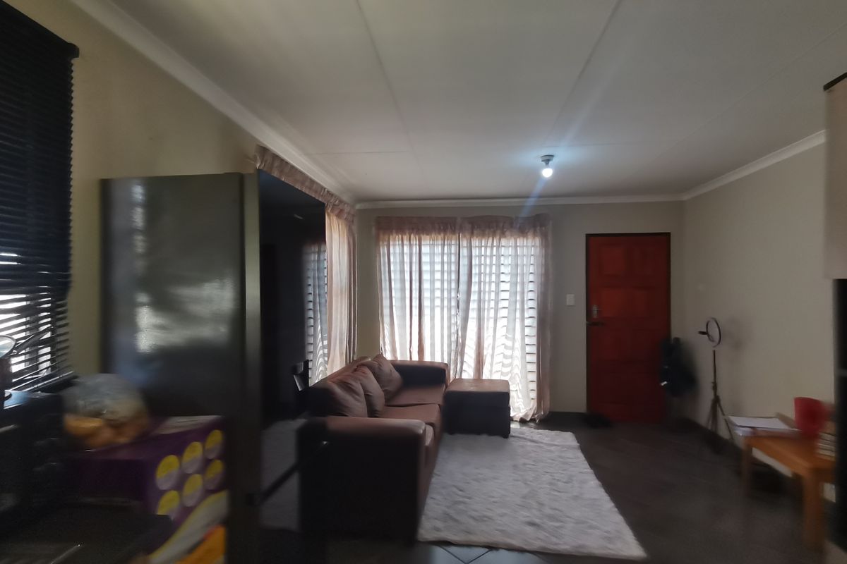 A living room area featuring tiled flooring, coved ceilings, and a sliding glass door providing access to the exterior.