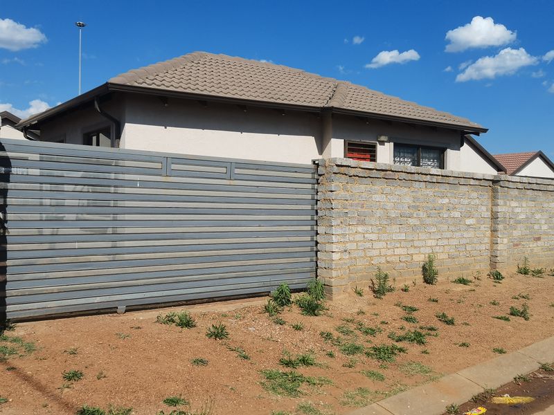 Front view of a residential property featuring a sliding metal gate, brick boundary wall, and concrete tile roof.