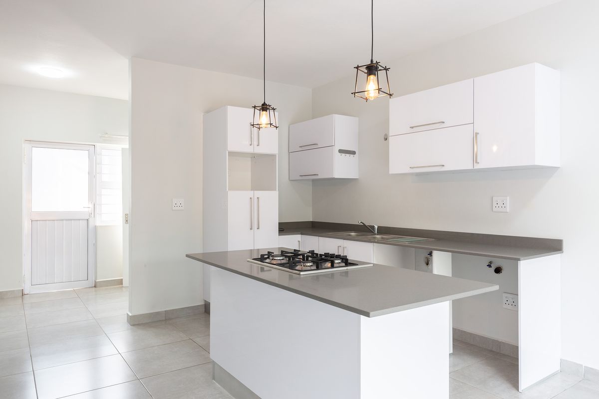 Modern kitchen featuring white cabinetry, stone countertops, a central island with a gas hob, and tiled flooring. Ready for appliance installation.