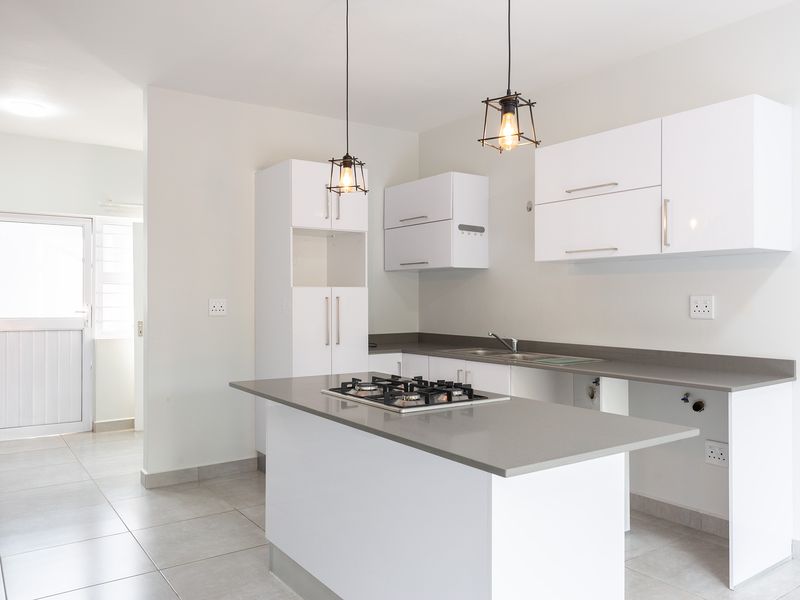 Modern kitchen featuring white cabinetry, stone countertops, a central island with a gas hob, and tiled flooring. Ready for appliance installation.