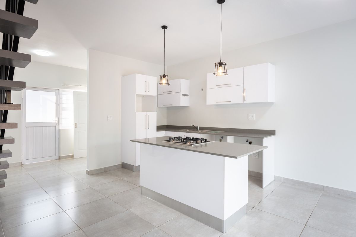 Modern kitchen featuring white cabinetry, stone countertops, a central island with a gas hob, and tiled flooring in an open-plan layout.