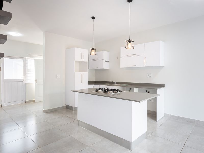 Modern kitchen featuring white cabinetry, stone countertops, a central island with a gas hob, and tiled flooring in an open-plan layout.