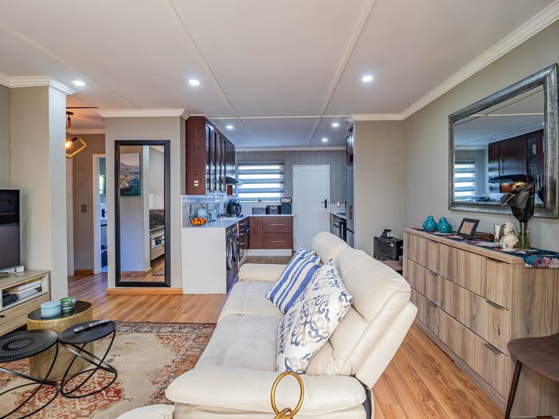 A well-maintained open-plan living and kitchen area featuring laminate flooring, modern cabinetry, and recessed lighting, creating a cohesive and functional living space.