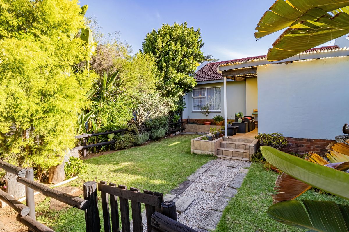 A well-maintained rear garden featuring a stone pathway, tiled patio area, and established landscaping, providing a private outdoor space for the townhouse.