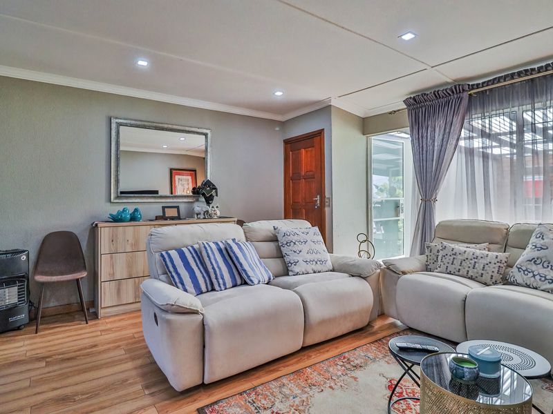 A comfortable living room featuring laminate flooring, recessed downlighting, and direct access to an outdoor patio area through a sliding glass door.