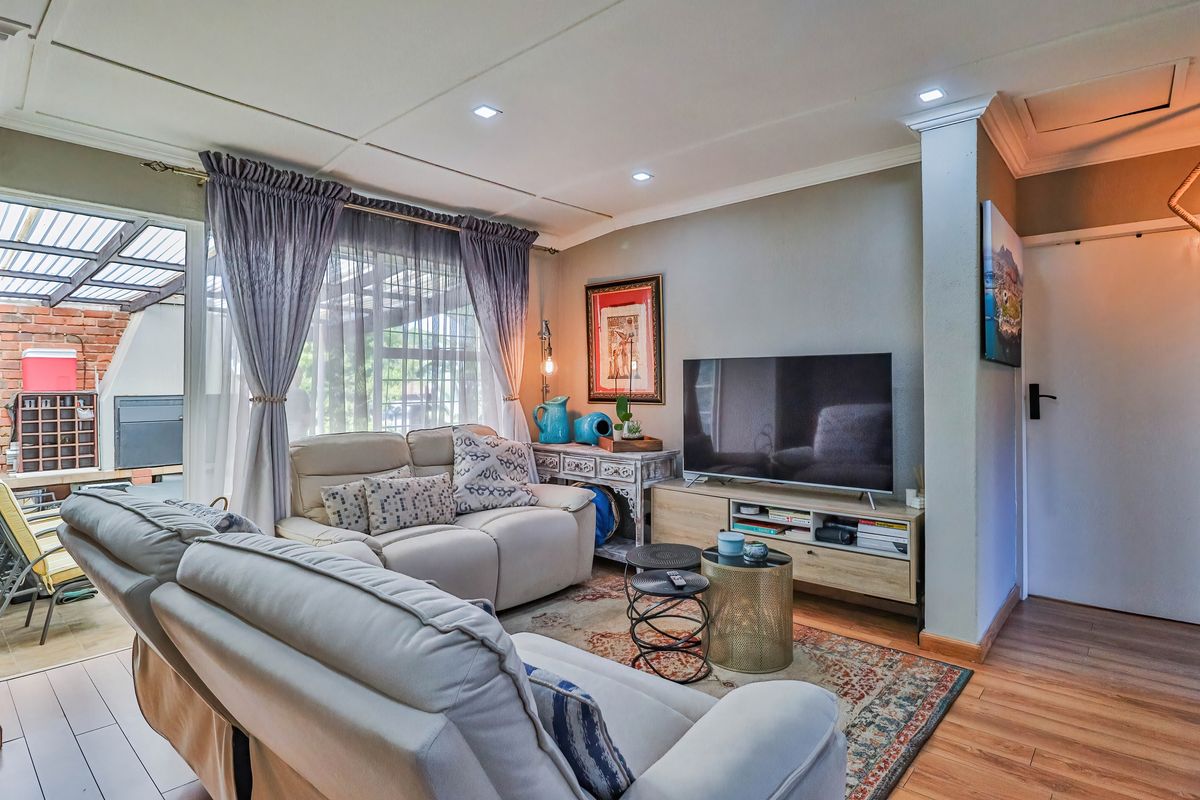 A comfortable living room featuring laminate flooring, recessed ceiling lighting, and a sliding glass door providing access to an outdoor patio area.