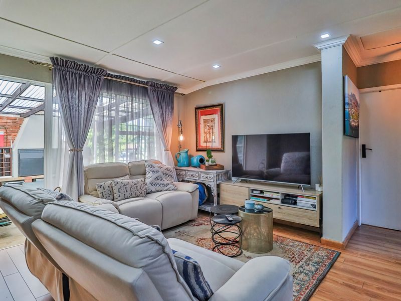 A comfortable living room featuring laminate flooring, recessed ceiling lighting, and a sliding glass door providing access to an outdoor patio area.