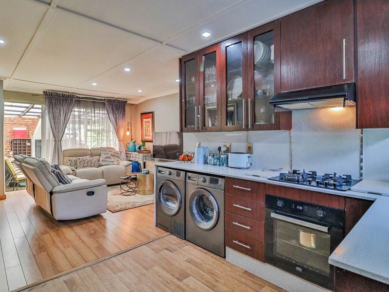 Open-plan living area featuring a modern kitchen with dark wood cabinetry, stone countertops, integrated appliances, and seamless flow to the lounge space.