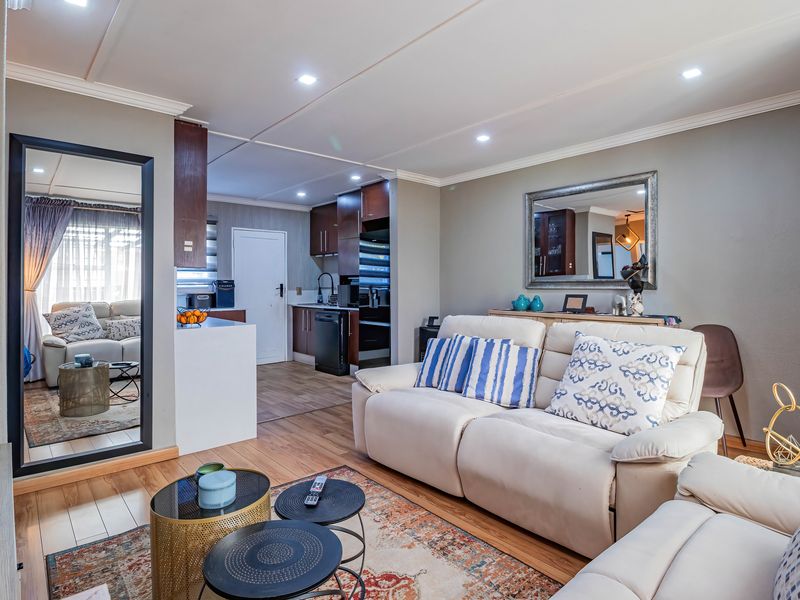 An open-plan living area featuring laminate flooring, recessed lighting, and a modern kitchen with built-in cabinetry, creating a cohesive and functional living space.