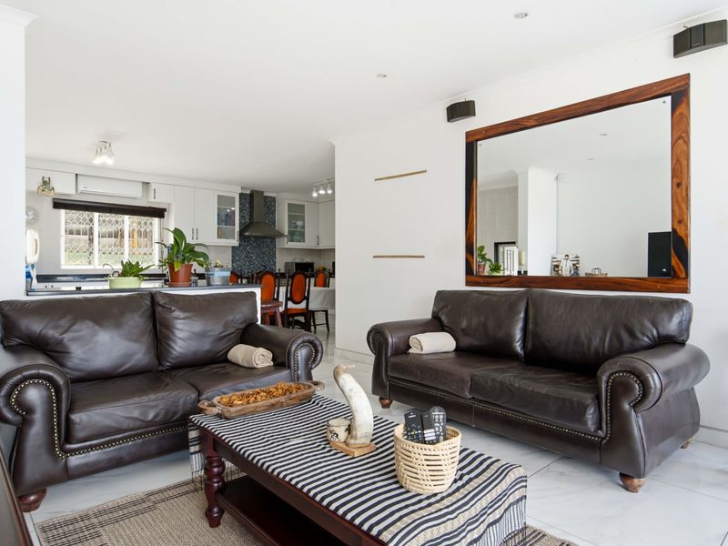 An open-plan living and kitchen area featuring tiled flooring, recessed lighting, and a functional kitchen layout with built-in cabinetry and an extractor fan.