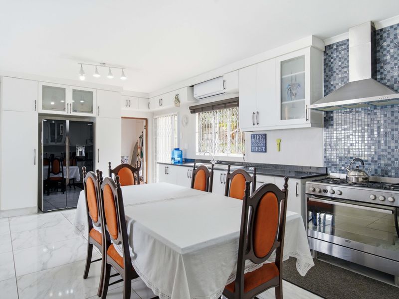 Open-plan kitchen and dining area featuring white cabinetry, granite countertops, mosaic tile backsplash, and stainless steel gas stove.
