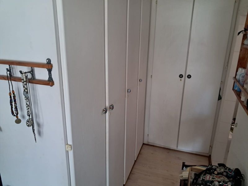 A bedroom area featuring extensive built-in cupboards and light-toned laminate flooring, offering ample storage space.