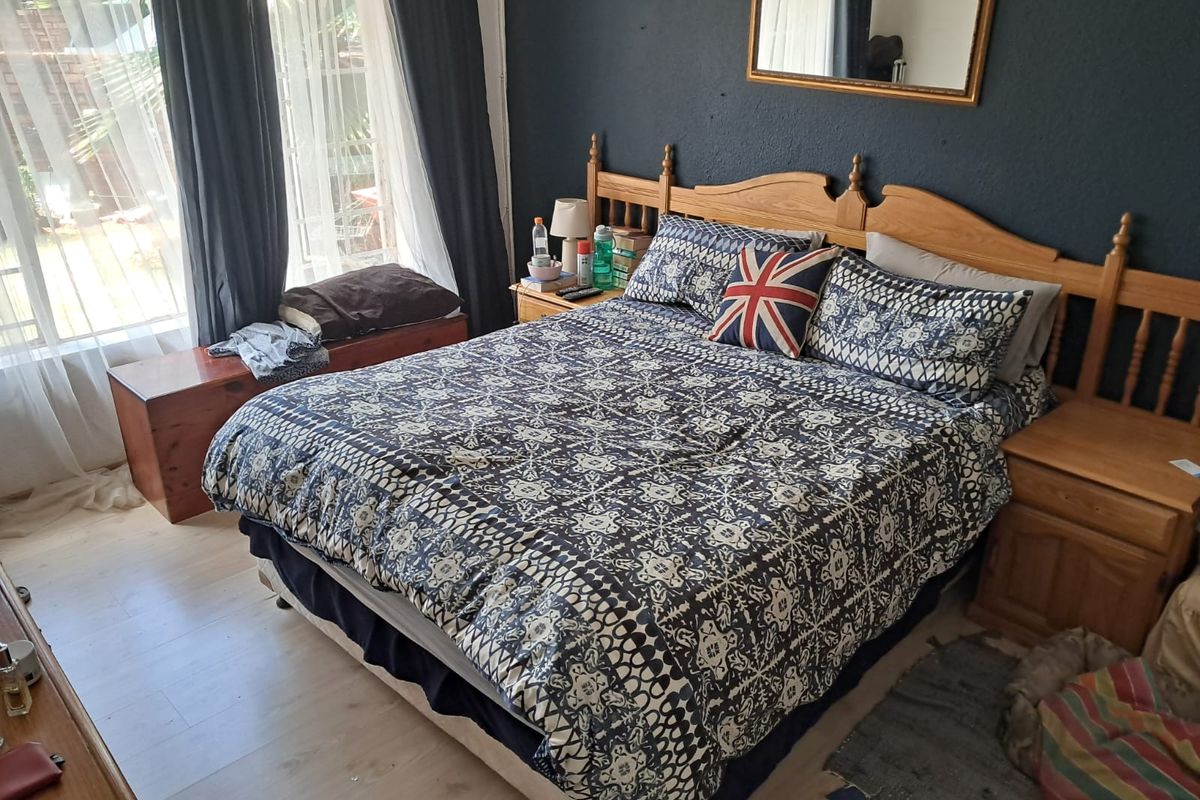 A bedroom featuring laminate flooring and a sliding glass door providing natural light and access to the exterior.
