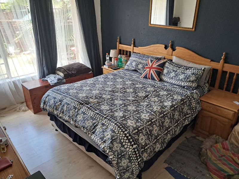A bedroom featuring laminate flooring and a sliding glass door providing natural light and access to the exterior.
