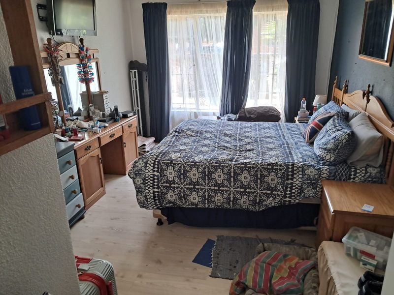 A functional bedroom featuring light-toned laminate flooring and large windows with curtain tracks, offering a neutral base for potential interior updates.