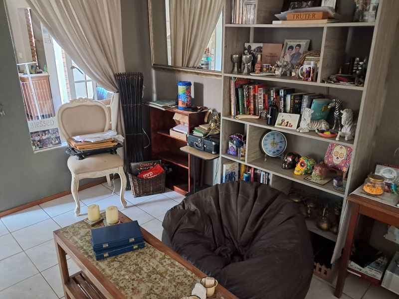 A living area featuring tiled flooring and a large built-in shelving unit, providing ample storage and display space.
