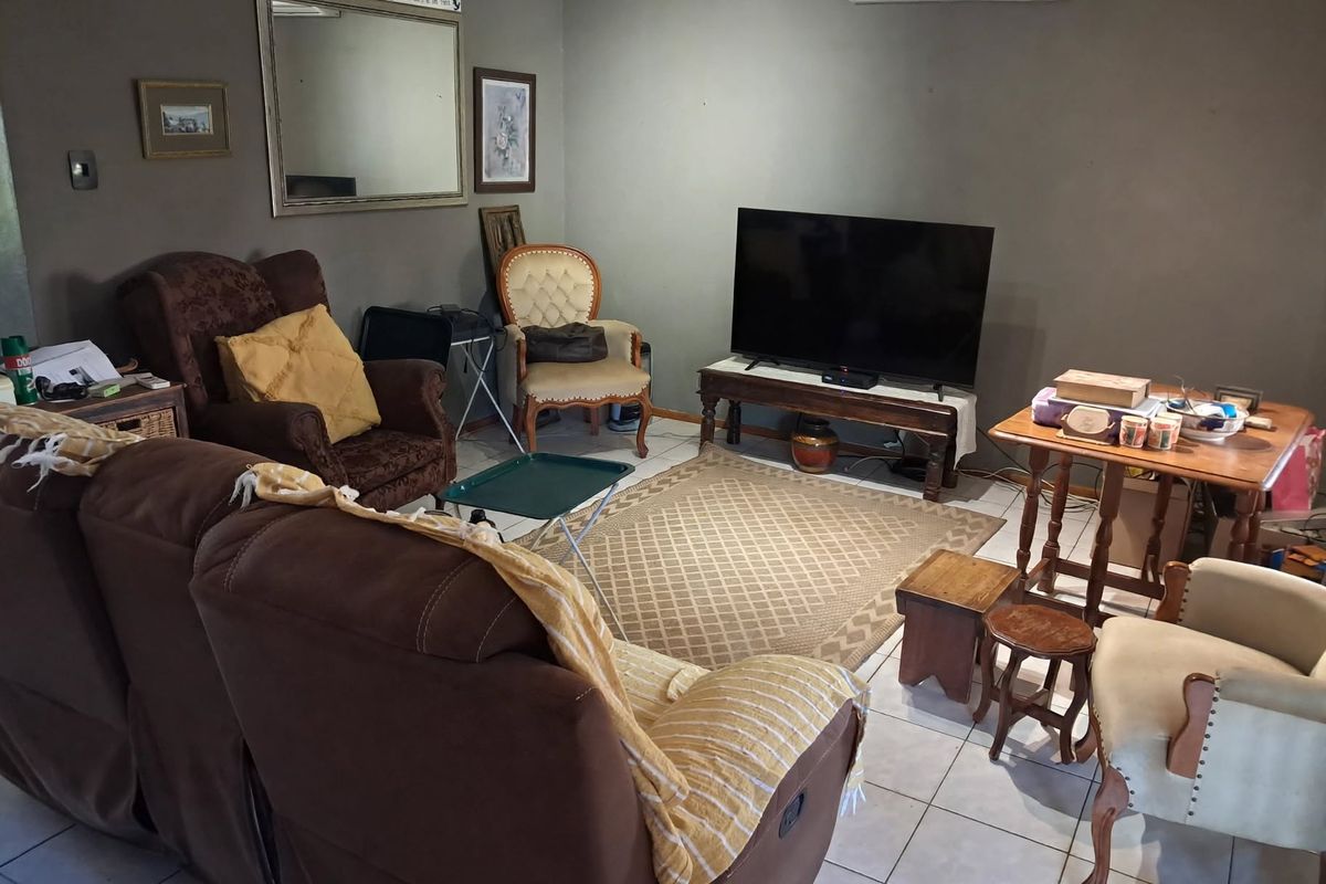 A living room featuring tiled flooring and a wall-mounted split-system air conditioning unit.