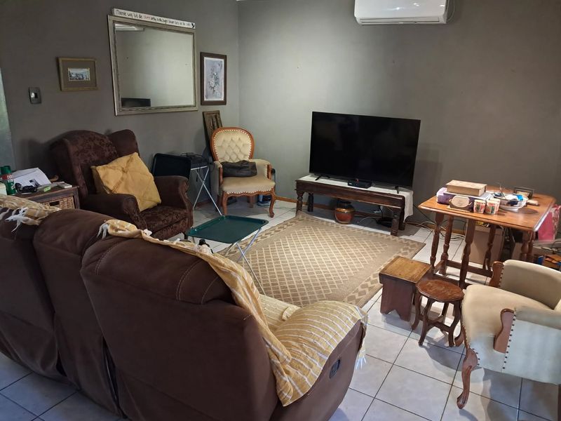 A living room featuring tiled flooring and a wall-mounted split-system air conditioning unit.