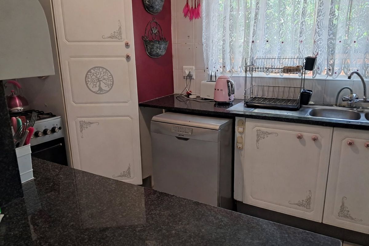 A functional kitchen featuring granite countertops, built-in cabinetry, and a tiled backsplash, offering a practical layout for daily meal preparation.