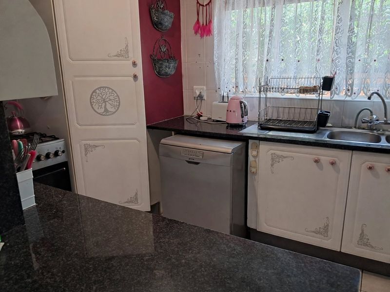A functional kitchen featuring granite countertops, built-in cabinetry, and a tiled backsplash, offering a practical layout for daily meal preparation.