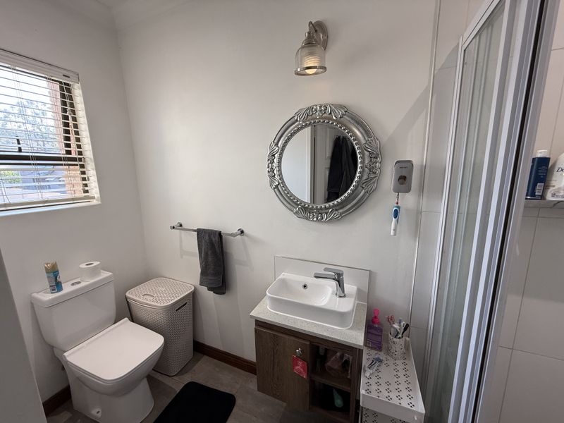 A functional bathroom featuring a modern vessel sink vanity, a toilet, and a glass-enclosed shower, complemented by neutral wall finishes and natural light.