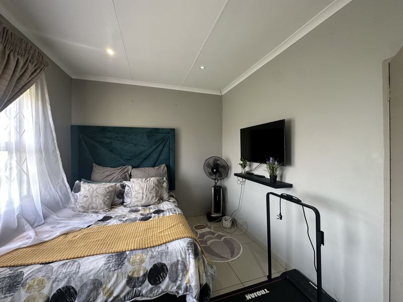 A functional bedroom featuring tiled flooring, recessed downlighting, and a coved ceiling, providing a neutral base for personalization.