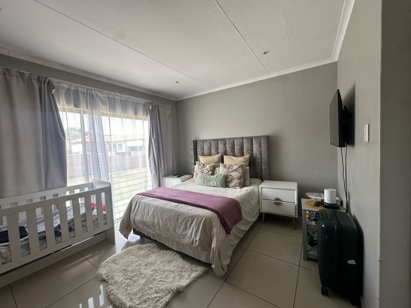 A well-maintained bedroom featuring large format floor tiles, neutral wall tones, and a sliding glass door providing access to the exterior.
