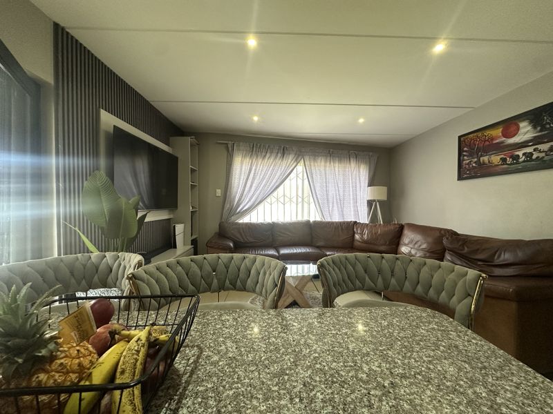 An open-plan living area featuring a granite kitchen island, recessed downlighting, and decorative wall paneling, creating a functional and cohesive living space.