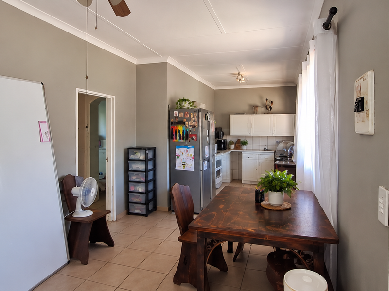 Open plan living and dining area featuring tiled flooring, a ceiling fan, and a functional kitchen with built-in cabinetry and appliances.