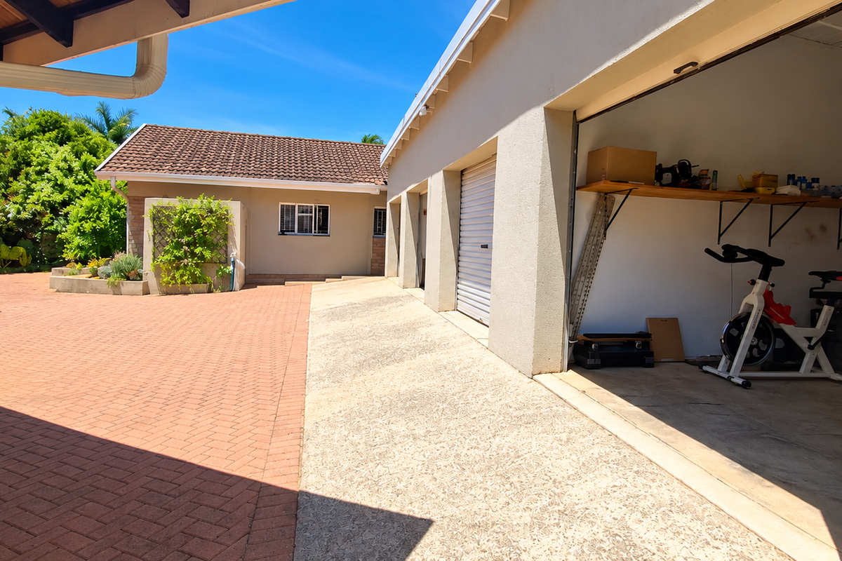 A spacious paved courtyard area featuring a multi-car garage with roller doors and well-maintained exterior building facades.