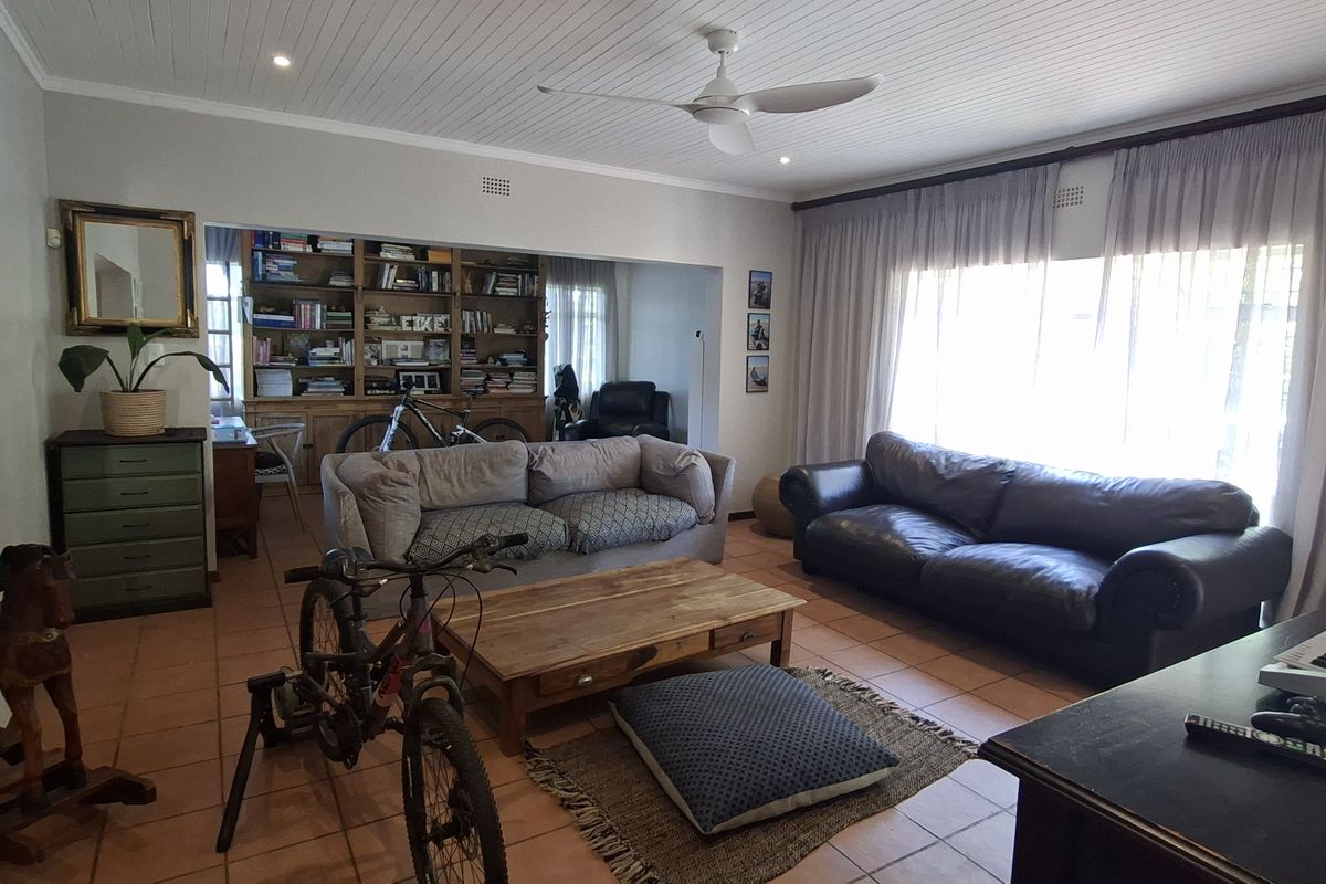 Spacious living room featuring tiled flooring, a tongue and groove ceiling with a fan, and built-in shelving units.
