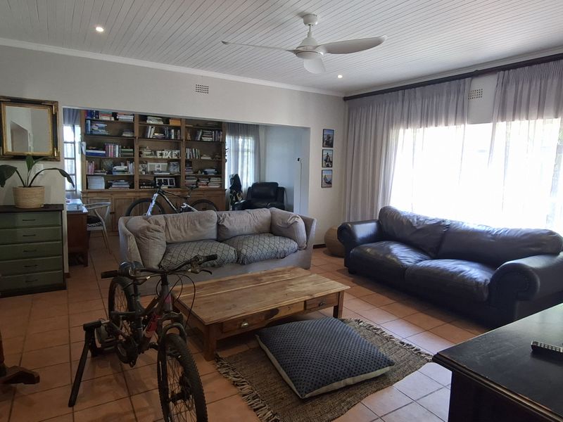 Spacious living room featuring tiled flooring, a tongue and groove ceiling with a fan, and built-in shelving units.